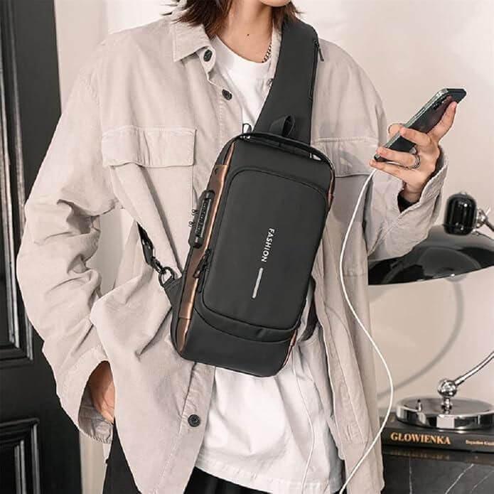 Black sling bag for men and women worn crossbody with phone and charging cable in casual outfit