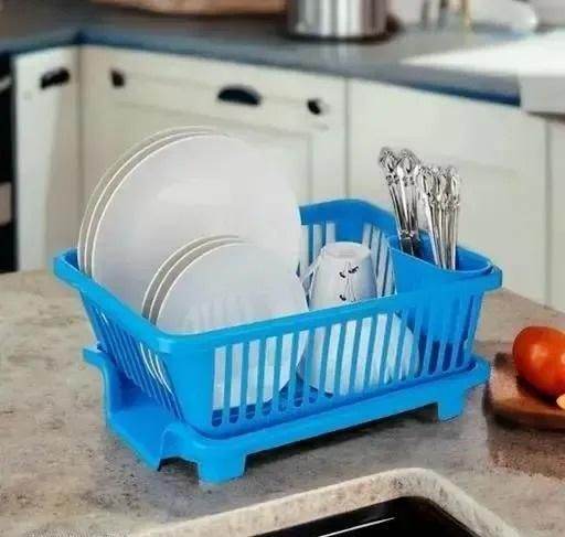 Blue kitchen dish drainer rack holding white plates, cups, and silver utensils on countertop