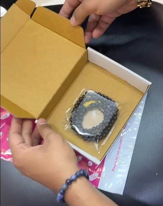 Hands opening a box containing karungali mala original 108 beads in clear plastic packaging