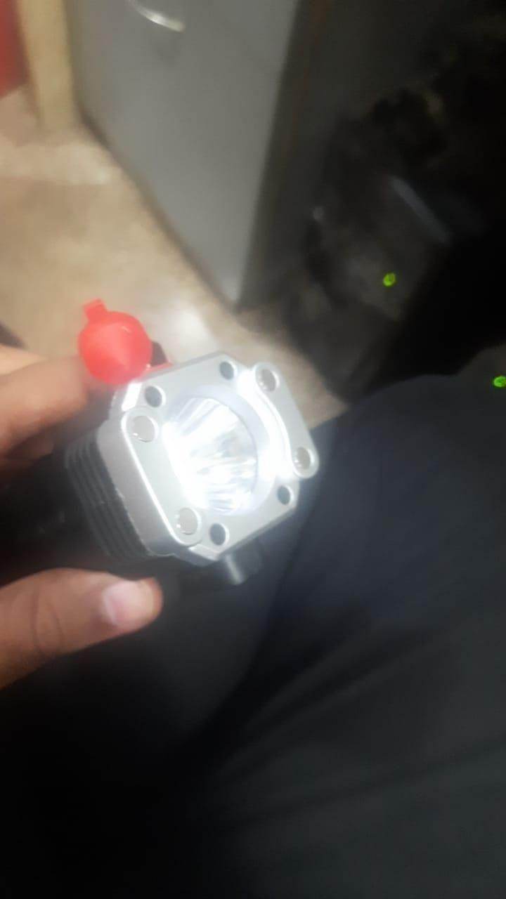 Hand holding a portable rechargeable LED flashlight with a red button and silver reflector