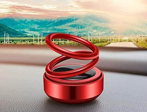 Red solar aromatherapy car accessory with spiral design sitting on car dashboard against scenic mountain background