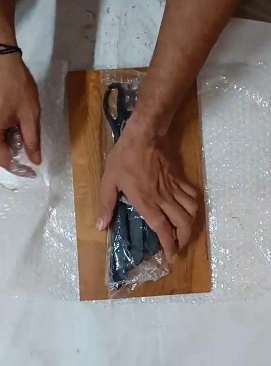 Person unwrapping stainless steel knives for home use on a wooden cutting board