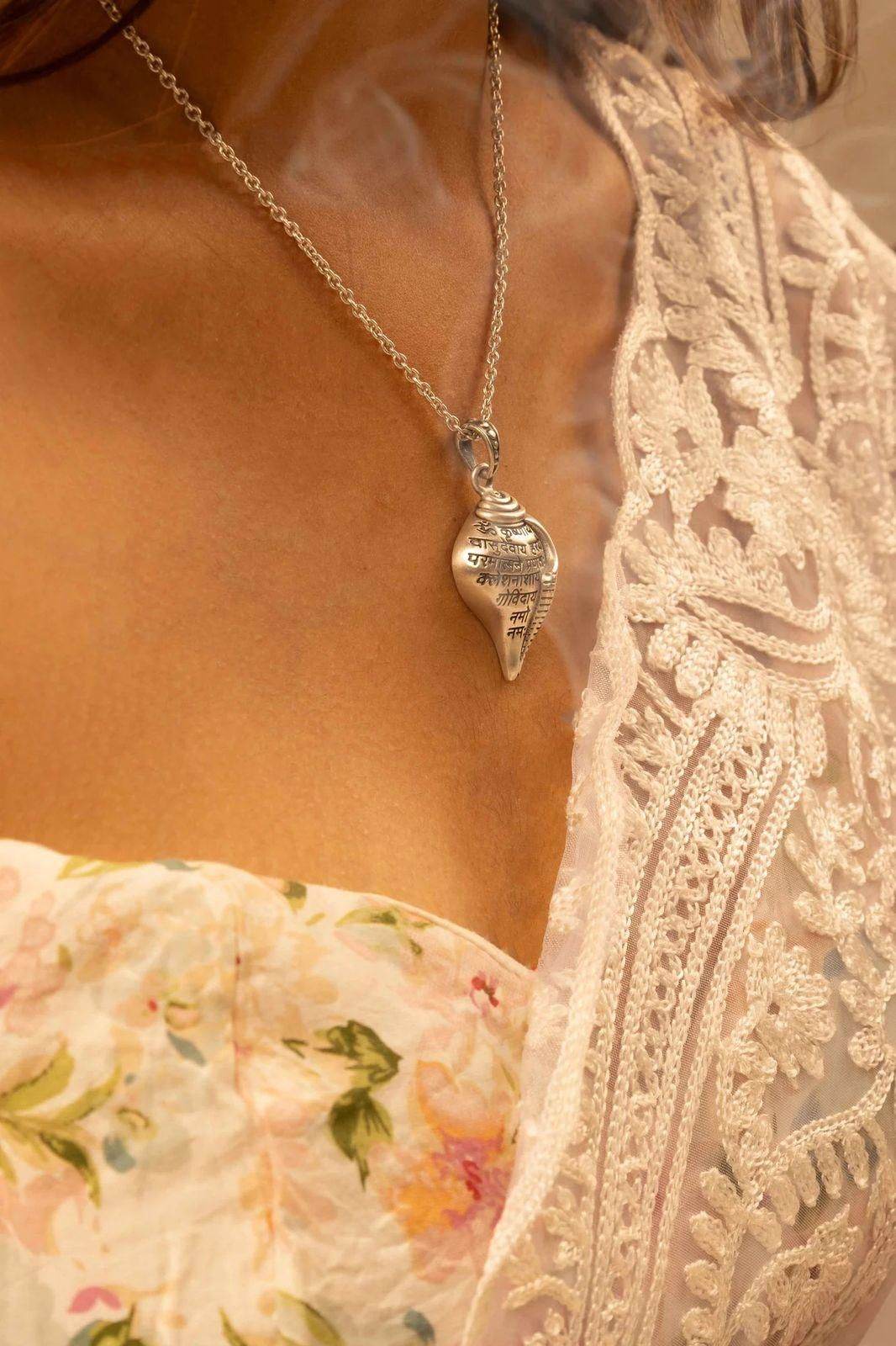 Shri Krishna conch pendant necklace worn on a silver chain with floral and lace attire