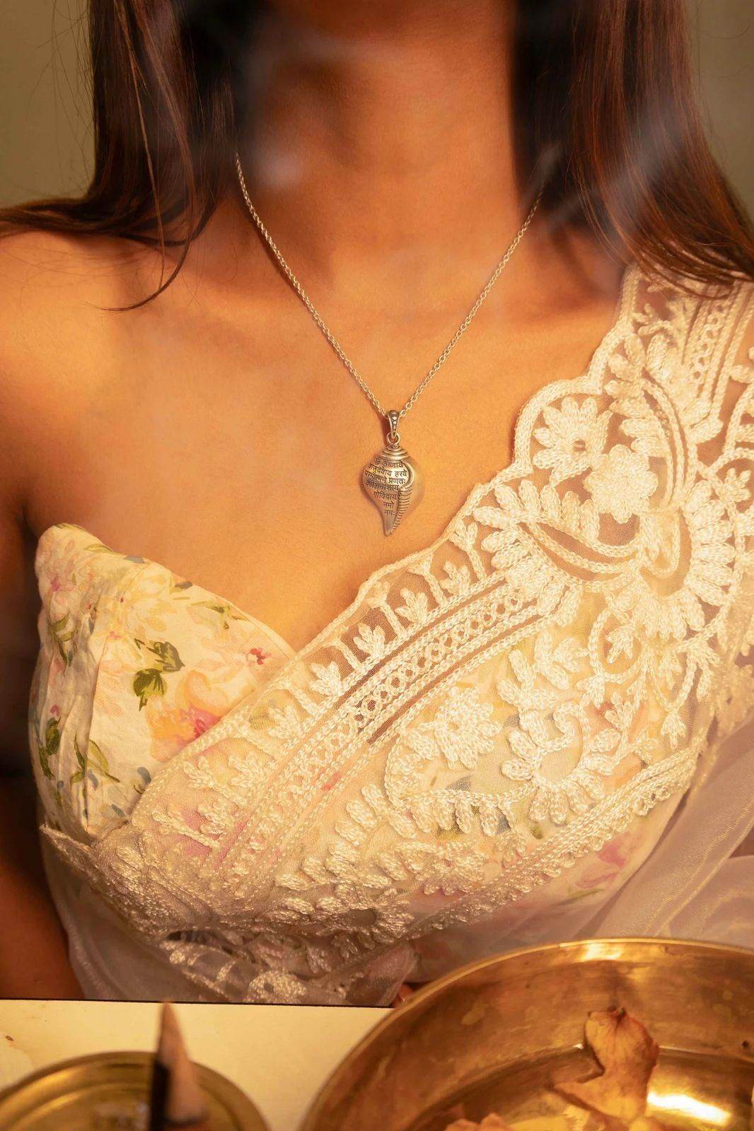 Shri Krishna conch pendant necklace worn by woman in floral and lace blouse