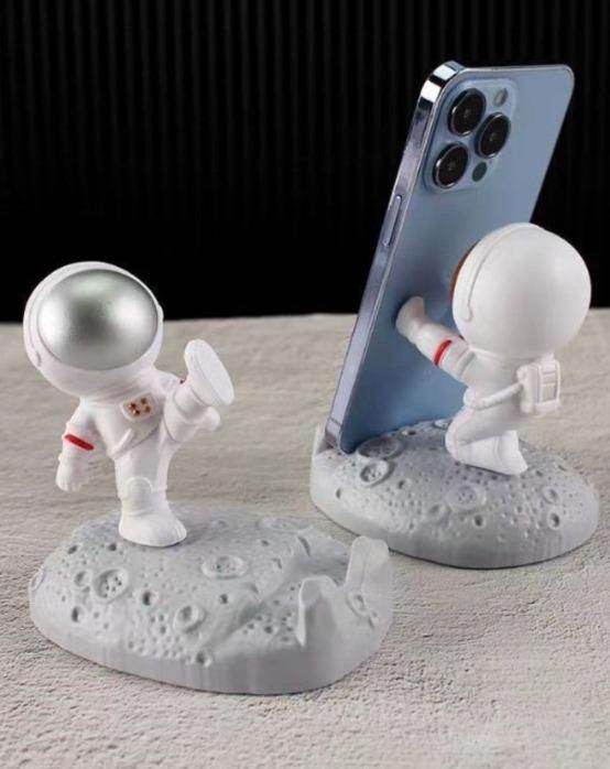 White astronaut phone stand holding smartphone with moon surface base in space design