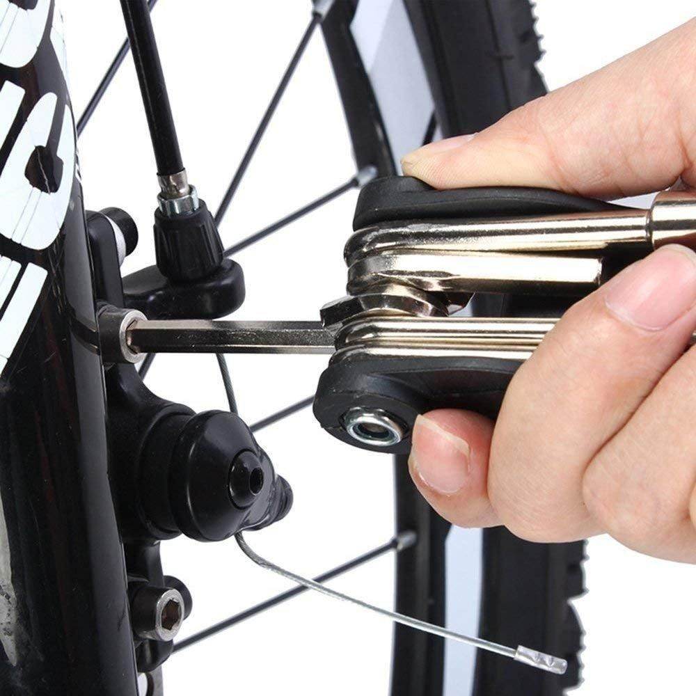 Hand using compact bicycle maintenance toolset to adjust a screw on a black bike wheel