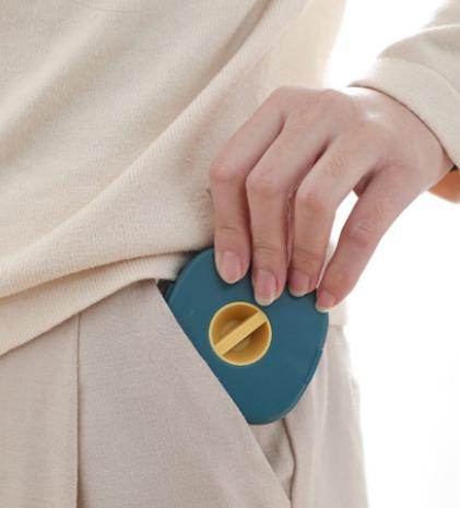 Person placing a compact USB cable holder into a beige pants pocket for easy carrying and storage