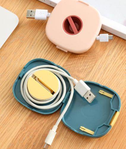 Compact USB cable holder in blue and pink colors organizing USB charging cables on a wooden surface