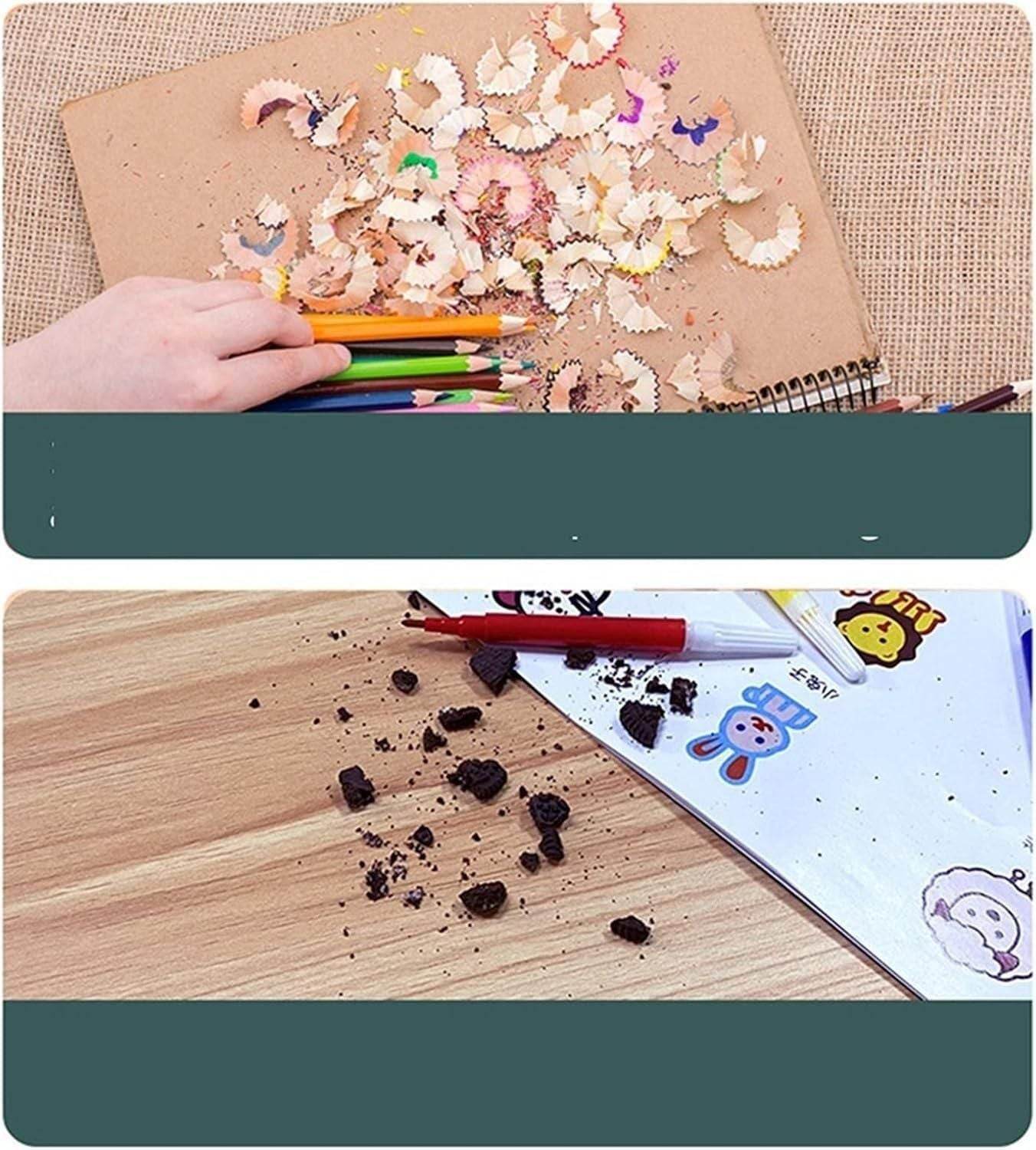 Hand holding colored pencils with pencil shavings on a notebook and broken pencil pieces scattered on a wooden surface