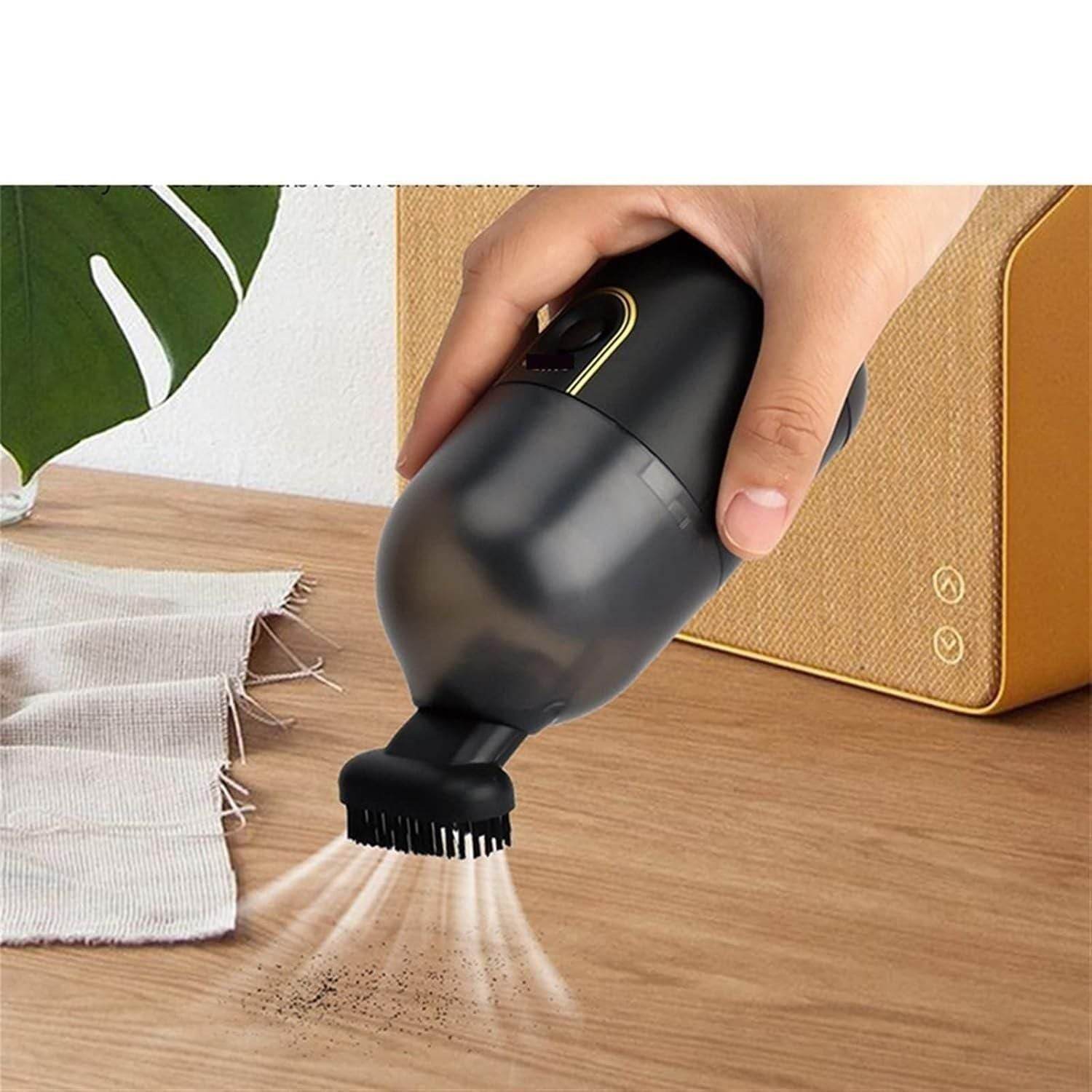 Handheld black mini vacuum cleaner removing dust from wooden surface with brush attachment
