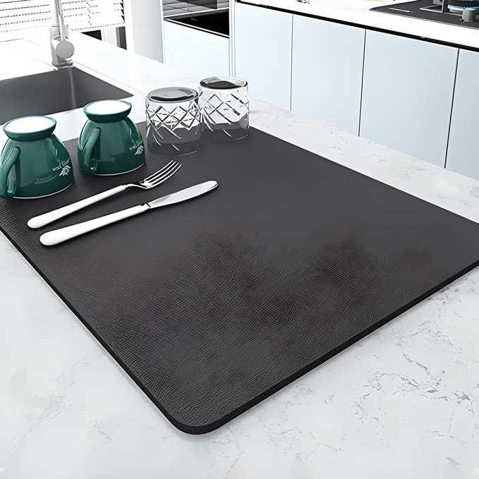 Black modern kitchen drying pad on a white marble countertop with cups, glasses, and utensils