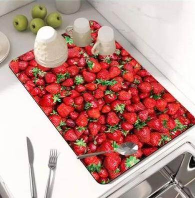 Modern kitchen drying pad with vibrant red strawberry design placed next to sink with dishes drying