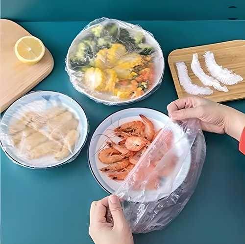 Hands covering plates of shrimp and assorted food with reusable food storage covers on a blue table