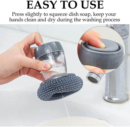 Kitchen soap dispensing palm brush with gray soap container being pressed over sink for dishwashing