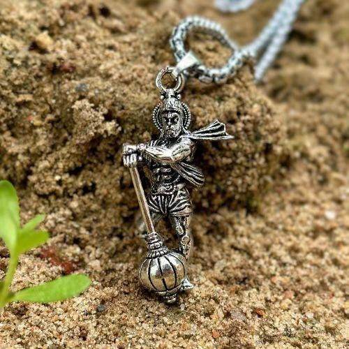 Silver Lord Hanuman pendant necklace with detailed figure resting on sandy surface