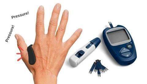Hand wearing a black sugar control acupressure clip next to glucose meter and lancets for diabetes monitoring
