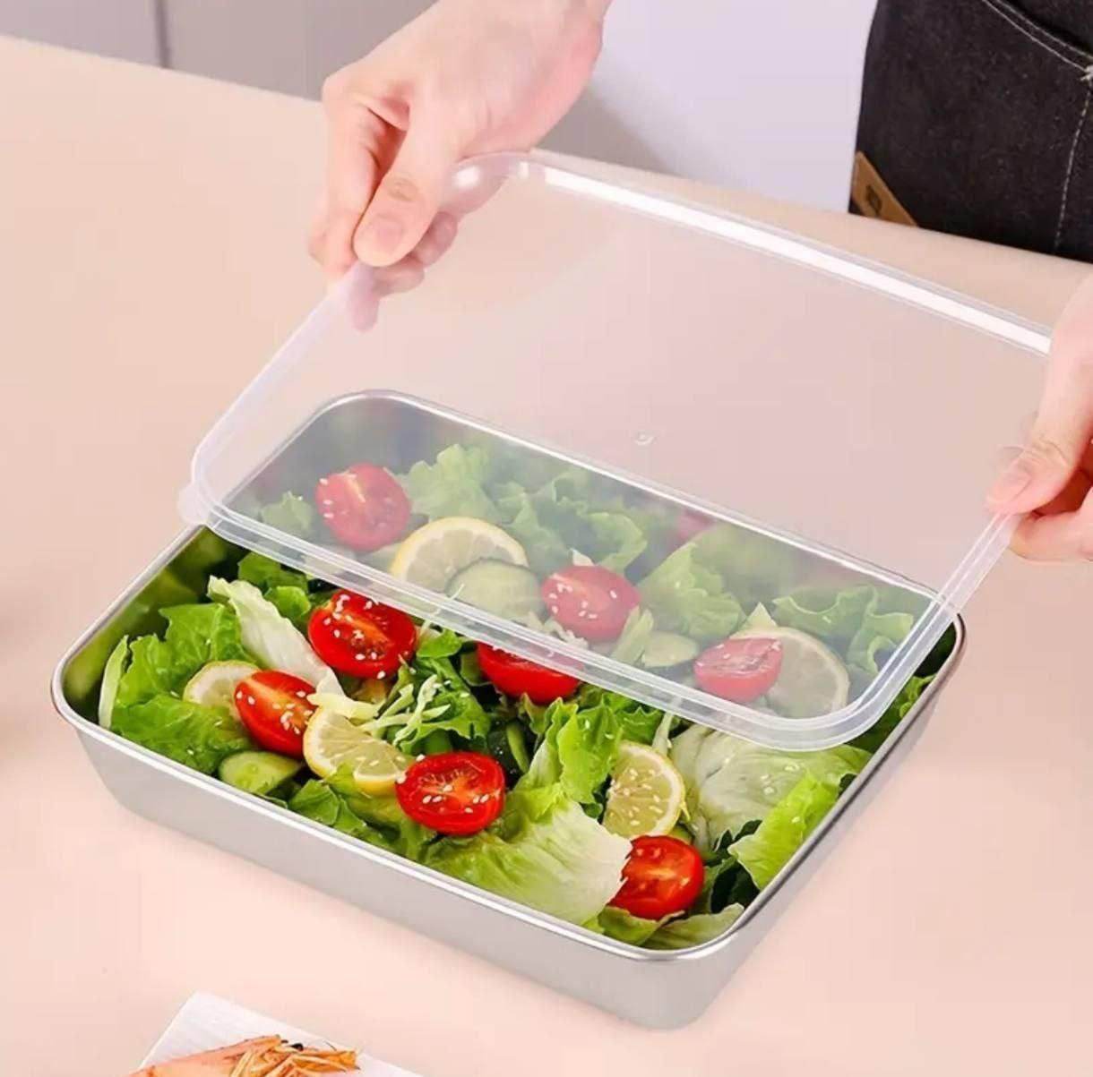 Multi-purpose kitchen container with cover holding fresh salad with lettuce cherry tomatoes and lemon slices