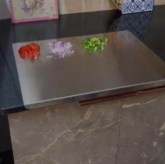 Stainless steel chopping board on kitchen countertop with chopped vegetables neatly placed