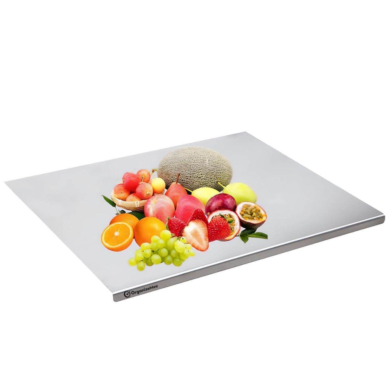 Stainless steel chopping board with assorted fresh fruits including melon, strawberries, grapes, and oranges on top