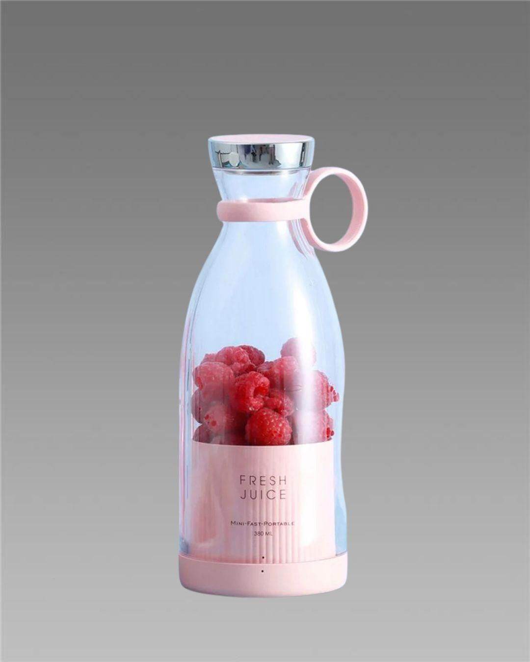 Portable mini juice blender with clear body and pink base filled with fresh raspberries