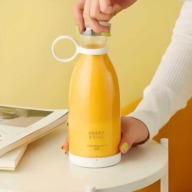 Yellow portable mini juice blender with a white base and cap being held on a white table