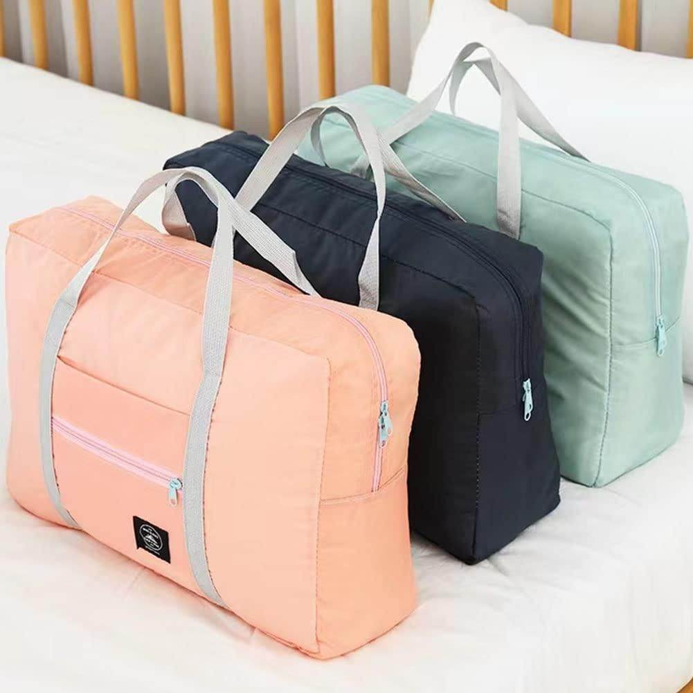 Three foldable travel tote bags in peach, black, and mint green with handles and front pockets