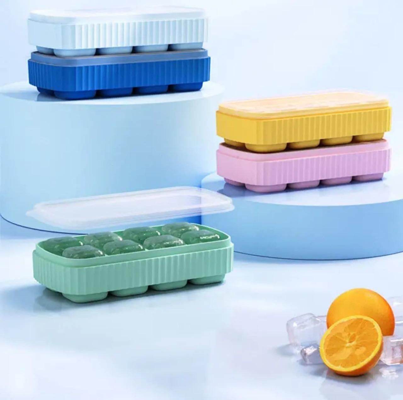 Colorful small ice cube mold for cocktails in blue, yellow, pink, and green with clear lids and orange slices