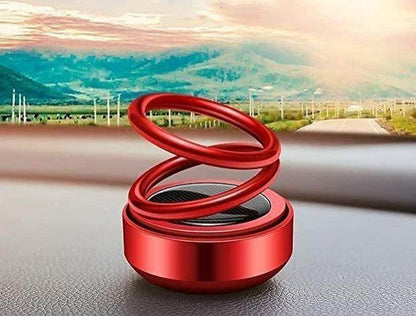Red solar aromatherapy car accessory with spiral design on car dashboard against mountain background