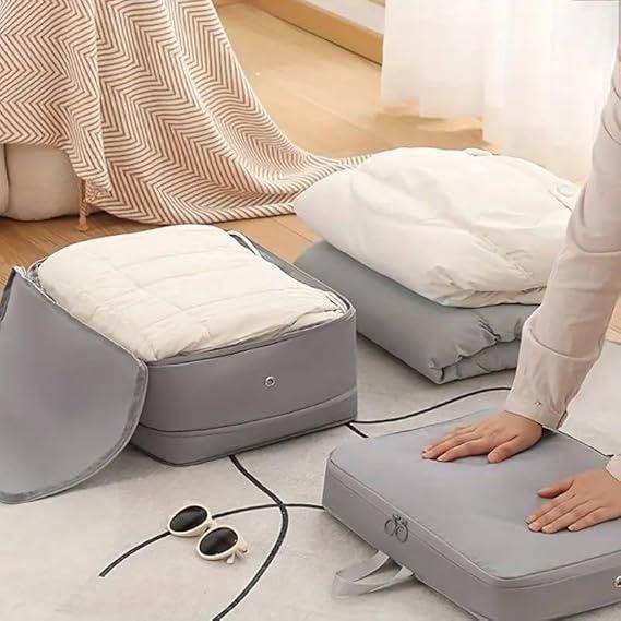Gray space saving luggage organizer being compressed to save room while storing blankets and clothes