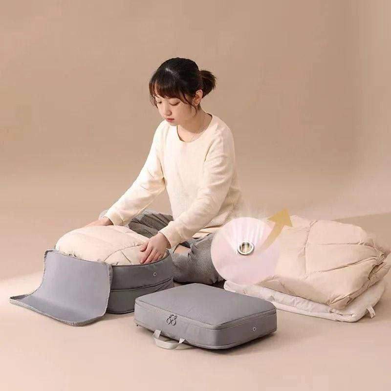 Woman using gray space saving luggage organizer to compress and pack bulky bedding efficiently