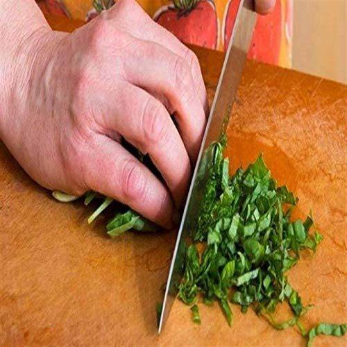 Hand using stainless steel knives for home use to chop fresh green herbs on wooden cutting board