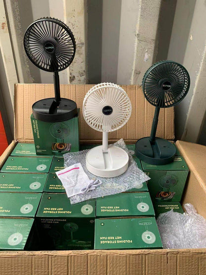 Three rechargeable table fans in black, white, and green displayed on packaging boxes inside a cardboard box