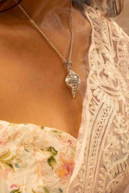 Shri Krishna conch pendant necklace worn on a silver chain with floral and lace attire